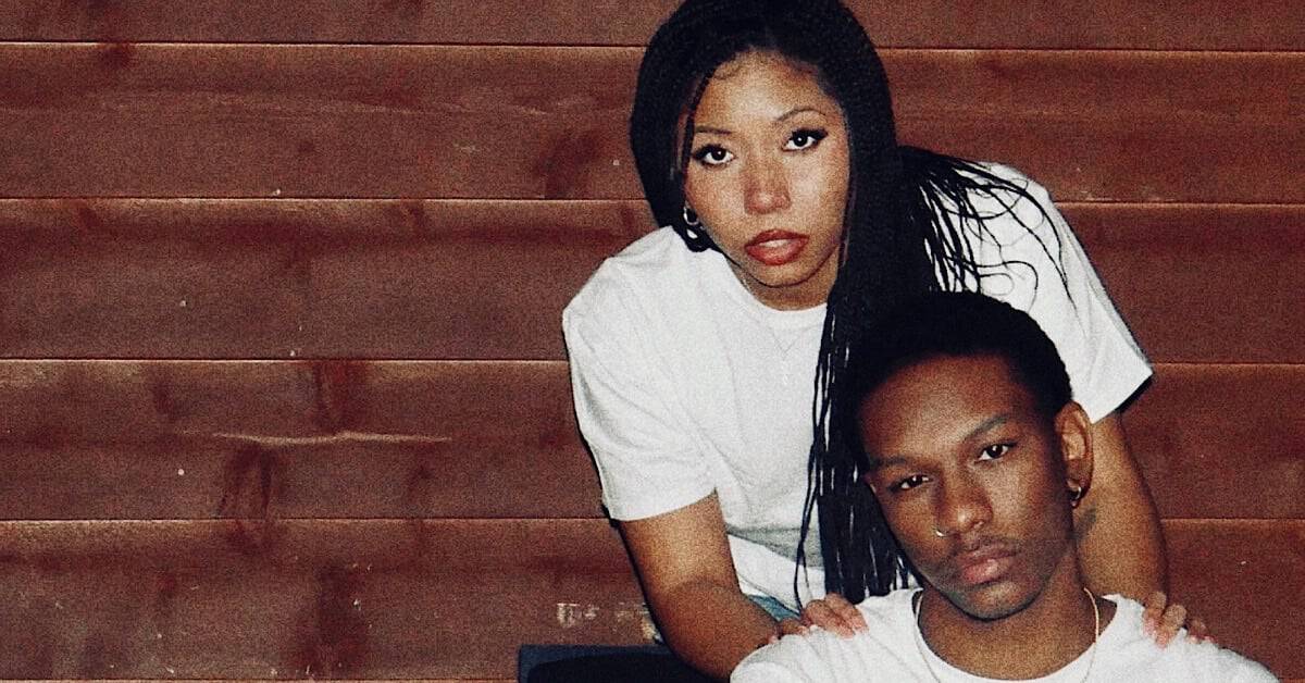 Two artists, Tre Nash and Jenesis, posing together on wooden stairs.