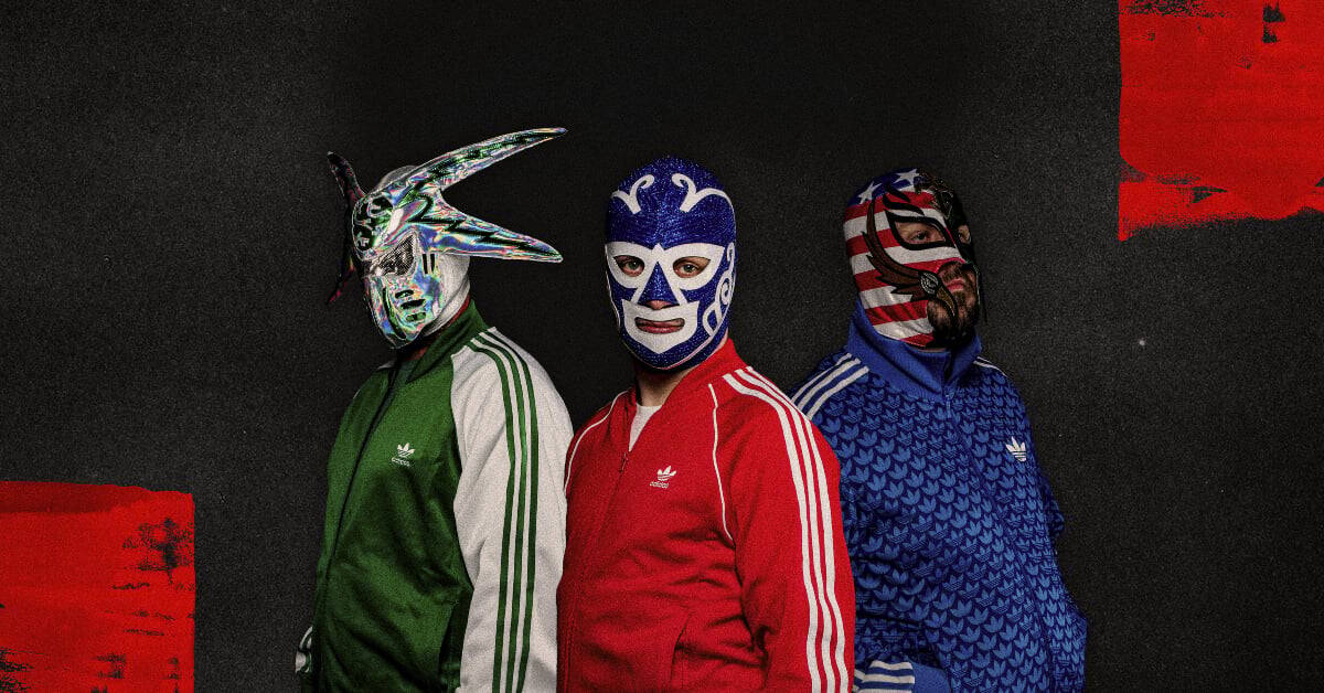 Three individuals in colorful lucha libre masks and sportswear against a dark background.