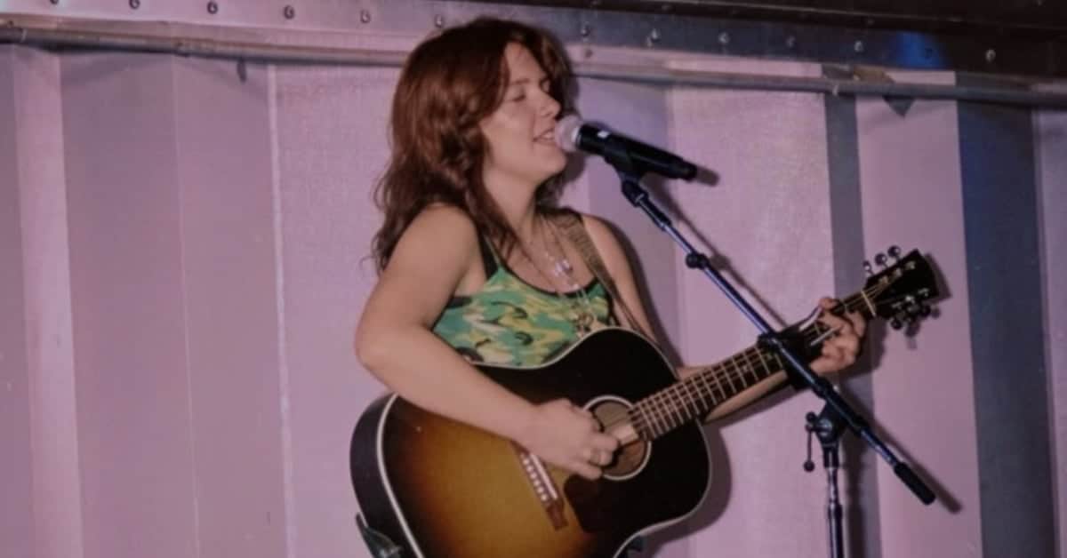 Ciera MacKenzie singing and playing guitar on stage.