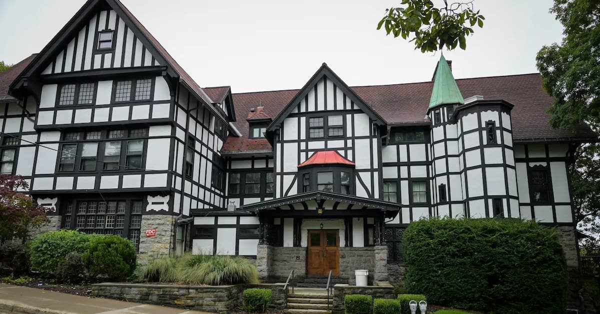 Historic Tudor-style building with black and white timber framing and green roof.