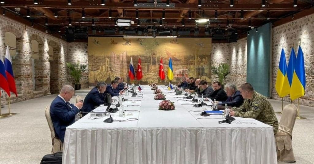 Delegates from Ukraine, Russia, and Ukraine flags at peace talks.